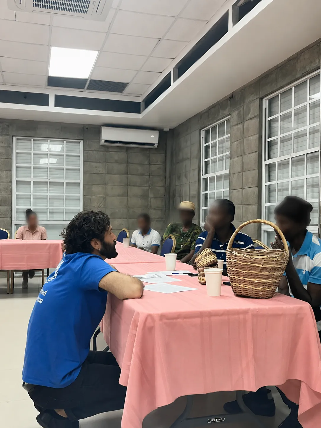 Francesco seated at a table in Grenada, leaning in and listening to people receiving government assistance during a focus group